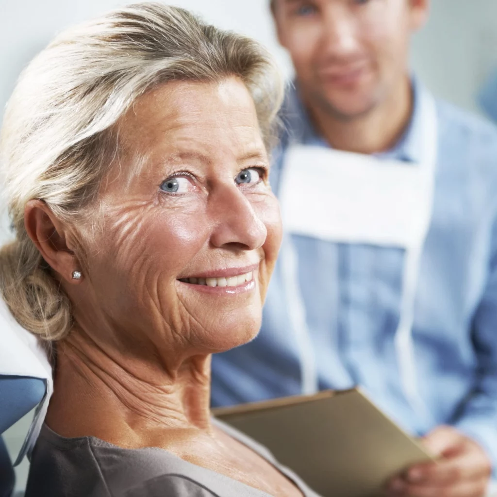 elderly woman smiling at dentist after sedation dentistry